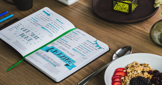 A young professional has written their goals in a notebook. The professional is focused on goals, organisation, and success. Writing tasks for the year ahead in colour-coded notes helps to get ahead and stay on track to achieve goals. 